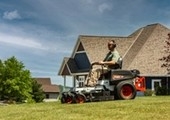 Male riding mower in front of house 
